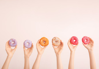 Fototapeta na wymiar Female hands with sweet donuts on color background