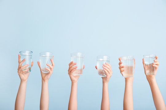 Female Hands With Glasses Of Water On Color Background