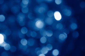abstract blurred circular bokeh lights background toned in trendy Classic Blue color of the Year 2020