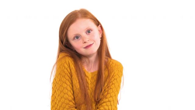 Portrait shot of a lovely little girl with long foxy hair and freckles with unpleased face expression posing at camera. Isolated, on white background