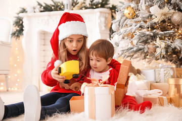 Fototapeta na wymiar Little children opening Christmas gifts at home