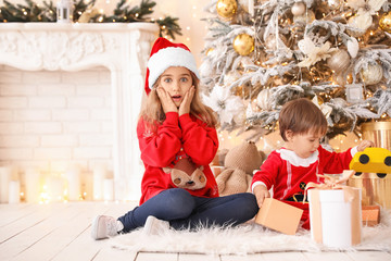 Little children opening Christmas gifts at home