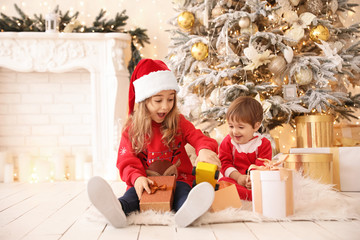 Little children opening Christmas gifts at home