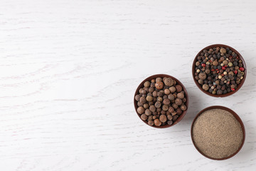 Ground pepper and corns on white wooden table, flat lay. Space for text