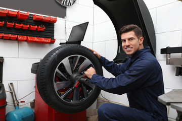 Obraz na płótnie Canvas Man working with wheel balancing machine at tire service