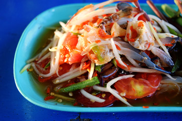 The picture of papaya salad crab in a blue dish is very appetizing with bright light.