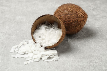 Tasty coconut chips and shell on grey table