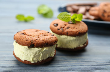 Sweet delicious ice cream cookie sandwiches on blue wooden table, closeup