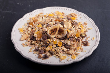 muesli with nuts and dry figs on dish on ceramic background