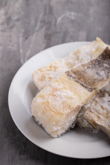 frozen cod fish on white dish on ceramic background