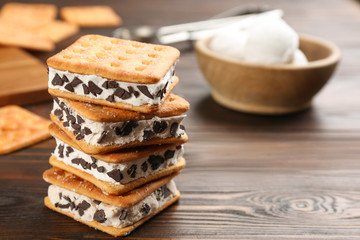 Sweet delicious ice cream cookie sandwiches on wooden table. Space for text