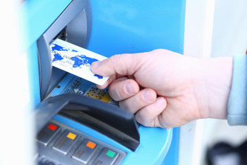 Male hand hold credit card aganist ATM
