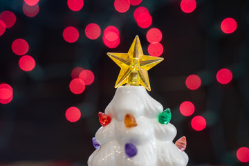 Vintage white ceramic Christmas tree, focus only on the star tree topper, with red bokeh background