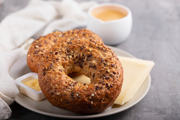 fresh bagels with butter and cheese on plate on ceramic background