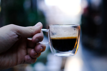 Transparent glass cup of coffee in the hand. Coffee in a cafe. 