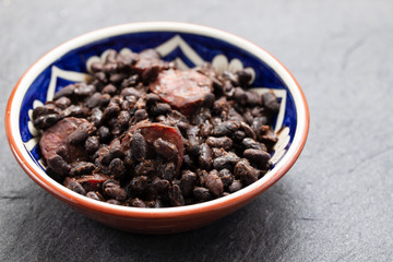 black beans with smoked sausages in ceramic dish