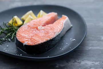raw salmon with rosemary and lemon on dark plate