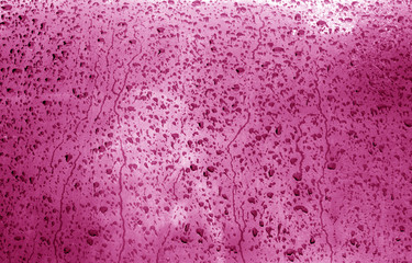 Water on blurred window in pink tone.