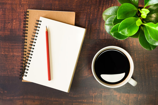 Top view of open school notebooks with blank pages, Pencil, Plant and Coffee cup on wooden table background. Business, office or education concept with copy space. flat lay