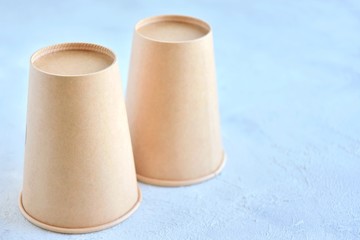 Two Recycling craft paper cups of coffee to go on neutral background with copy space. Selective focus. Craft cup for hot beverage, takeaway. Disposable cup. Eco package. Cardboard coffee cup