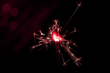 Sparkler in red and white light on a black background
