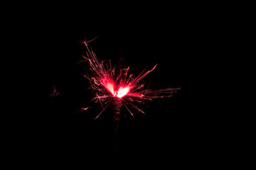 Sparkler in red and white light on a black background
