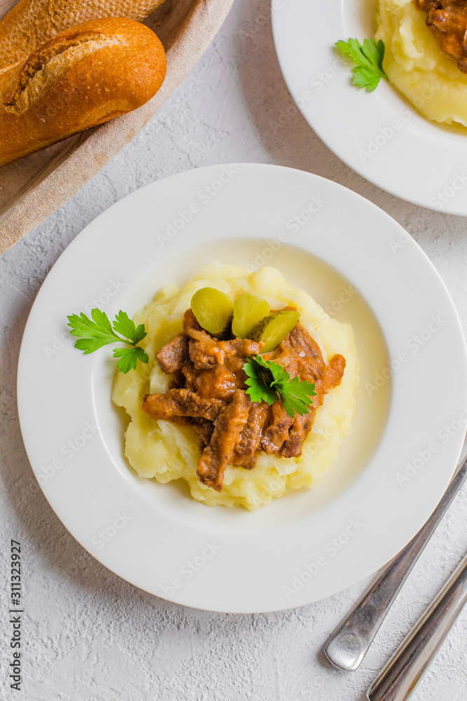 Wall mural Mushed potatoes and beef stew, decorated with pickles and parsley. Homemade dinner.