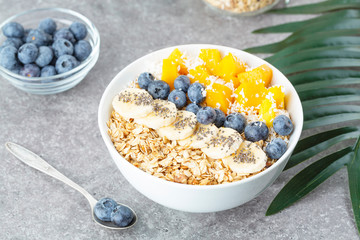 Healthy smoothie bowl with mango, blueberries, bananas, coconut, chia and granola. Healthy summer dessert.