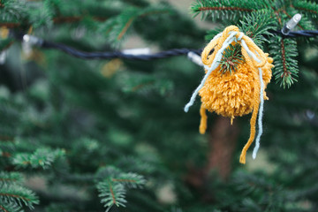 Wool handmade decoration on a Christmas tree outdoor. Diy yarn crafts creative ideas for children. Environment, recycle and zero waste concept. Selective focus, copy space.