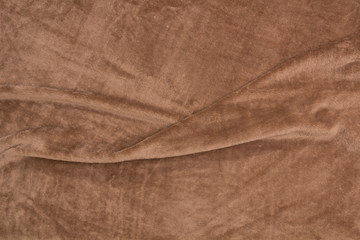 The blanket of furry fleece brown fabric. A background soft plush fleece material with a lot of relief folds