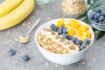 Healthy smoothie bowl with mango, blueberries, bananas, coconut, chia and granola. Healthy summer dessert.