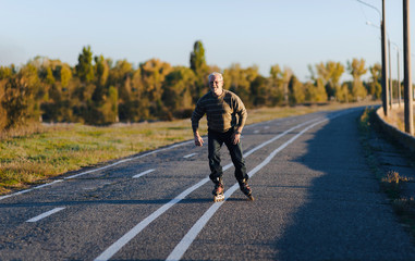 Obraz premium The old man goes on rollers in the autumn park. Happy pension. Active old people.