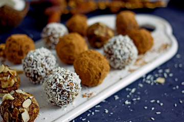 Raw Food Candy Balls. Handmade vegan sweets made of almonds, walnuts, dates, coconut and cocoa. Raw food candies in coconut flakes close-up. The concept of healthy vegan sweets, sugarless candie