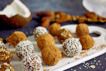 Raw food candy. Handmade vegan sweets made from almonds, walnuts, dates, raisins, coconut and cocoa. Raw food candies in coconut and cocoa close-up. Healthy vegan sweets concept.