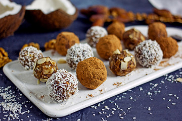 Raw food candy. Handmade vegan sweets made from almonds, walnuts, dates, raisins, coconut and cocoa. Raw food candies in coconut and cocoa close-up. Healthy vegan sweets concept.