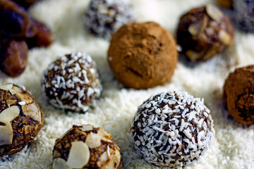 Raw Food Candy Balls. Handmade vegan sweets made of almonds, walnuts, dates, coconut and cocoa. Raw food candies in coconut flakes close-up. The concept of healthy vegan sweets, sugarless candie