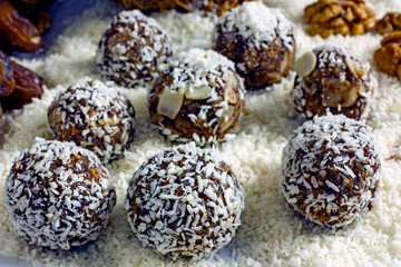 Raw Food Candy Balls. Handmade vegan sweets made of almonds, walnuts, dates, coconut and cocoa. Raw food candies in coconut flakes close-up. The concept of healthy vegan sweets, sugarless candie