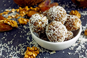 Raw food candy. Handmade vegan sweets made from almonds, walnuts, dates, raisins, coconut and cocoa. Raw food candies in coconut and cocoa close-up. Healthy vegan sweets concept.