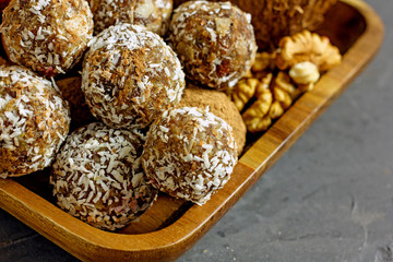 Raw Food Candy Balls. Handmade vegan sweets made of almonds, walnuts, dates, coconut and cocoa. Raw food candies in coconut flakes close-up. The concept of healthy vegan sweets, sugarless candie