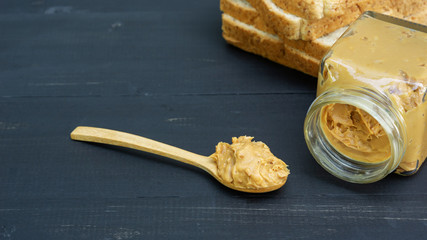 Peanut butter and whole wheat bread on a black wooden table.