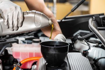 partial view of mechanic pouring motor oil at car engine