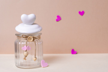 A glass can and a heart-shaped lid are on a light pink background. Close-up, copy space, layout design.