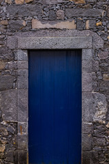 Typical ancient house made of volcanic rock with wood door painted blue in S. Miguel Island at Azores