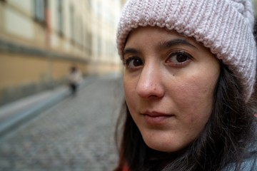 Young brunette girl close-up looking at camera with a cap on her head on the city of Prague, Czech Republic