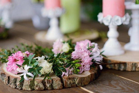 Beautiful wreath of spring flowers and green branches on a wooden round stand on the table.