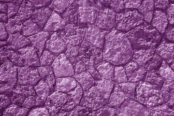 Wall made of old stones in purple tone.