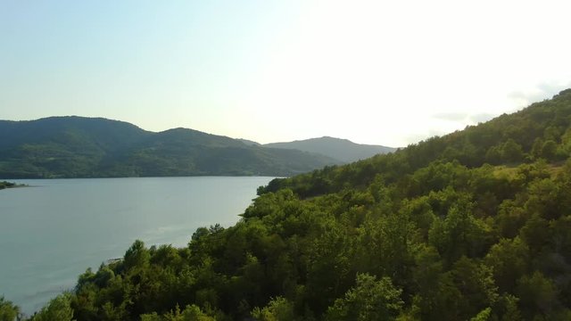 Forest edge of lake Butoniga water reservoir dam in Croatia with tall trees and shrubs, Aerial drone flyover shot