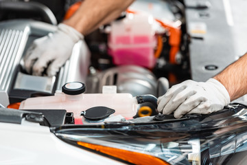 cropped view of mechanic inspecting car engine compartment