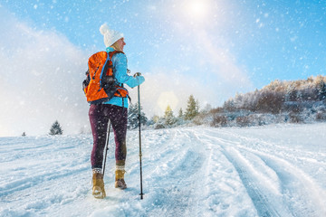 Happy woman tourist walking on the snowy trek on the peak of mou