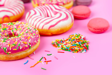 Donuts and macaroons on a pink background.
